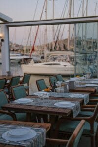 Charming outdoor cafe in İzmir overlooking a marina with yachts, perfect for relaxation.