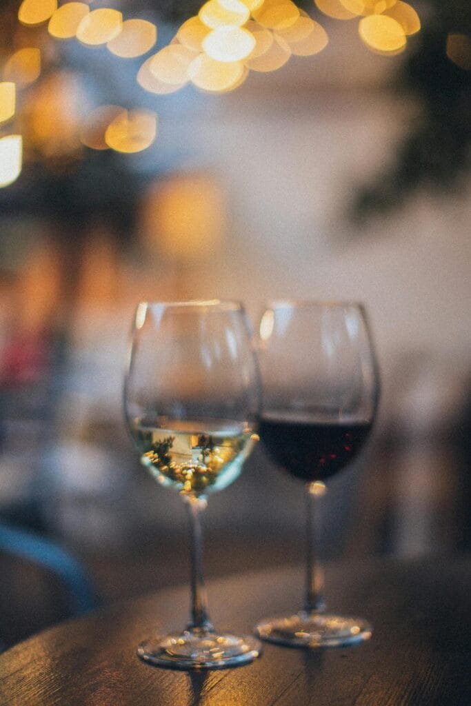 pexels-photo-3099654-3099654 Two wine glasses, red and white, on a table with a bokeh background, creating a warm ambiance.