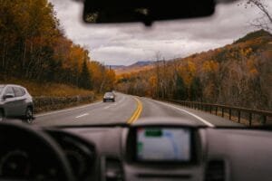 Driving on a scenic fall road, surrounded by colorful trees and mountains.