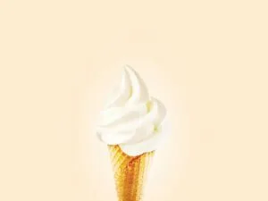 Close-up of a creamy soft serve ice cream cone on a bright background.
