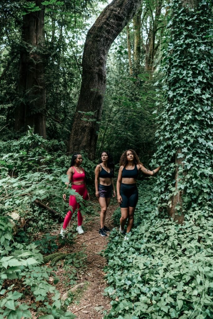 pexels-photo-8980986-8980986 Three women in activewear hiking through a lush forest trail, embracing nature.